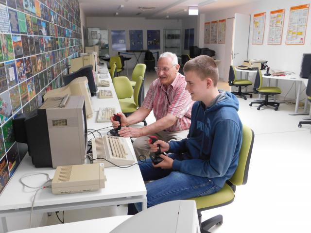 Nagyapa és unokája játszik a Commodore-64 számítógépen az NJSZT ITK interaktív videojáték kabinetjében